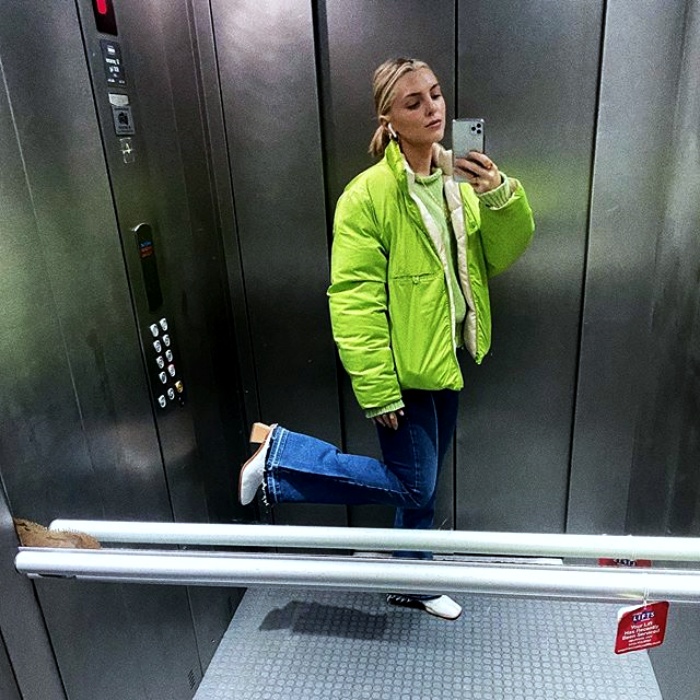 chica usando una chamarra color verde neón con jeans acampanados, botas blancas de tacon