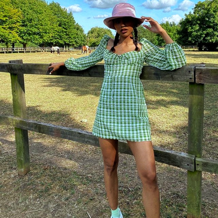 chica morena con bucket hat lila usando un vestido verde con cuadros blancos