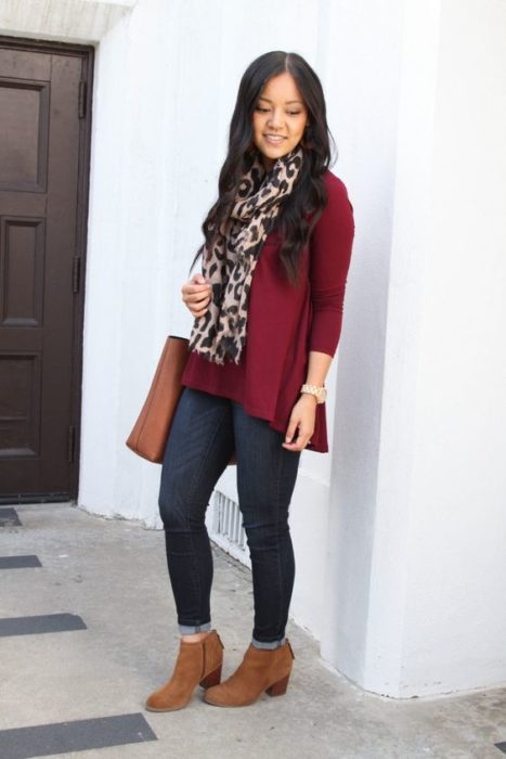Chica de cabello largo suelto con saco guinda, jeans oscuros y botines cafés