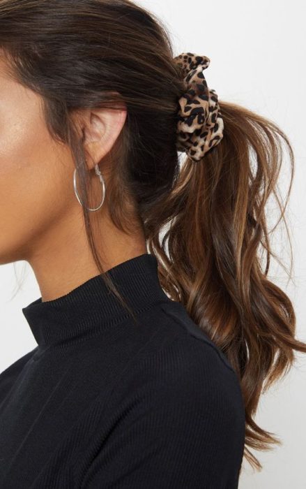 Chica peinada con coleta baja con un scrunchie de animal print