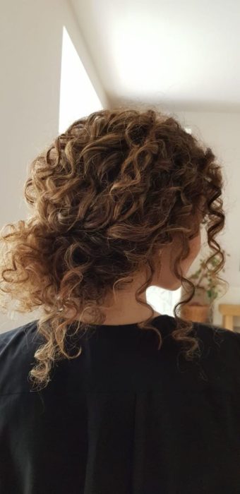 Chica con cabello rizado, recogido, manteniendo la textura visible