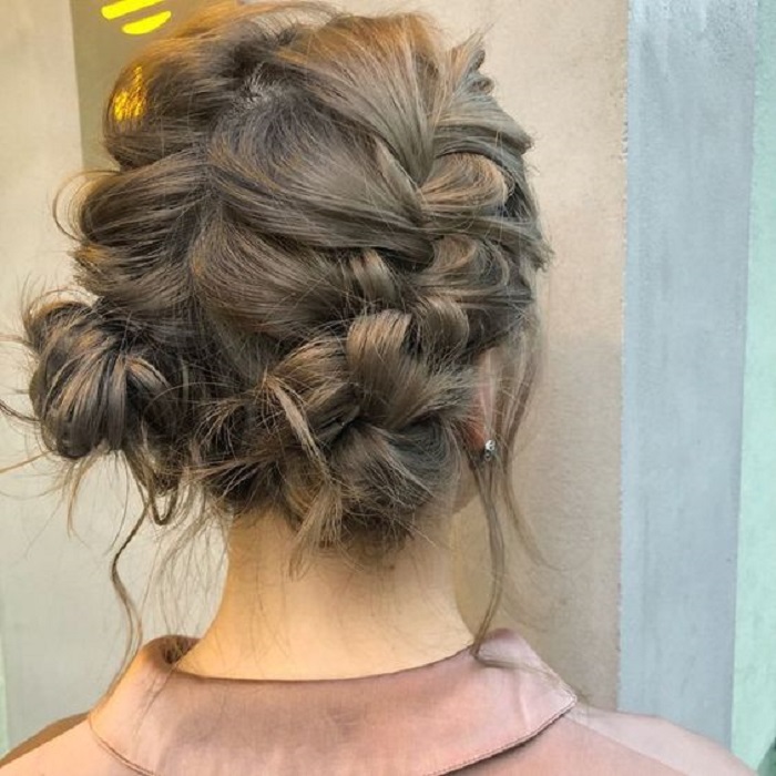 Chica con dos trenzas pegadas al cabello y moñitos