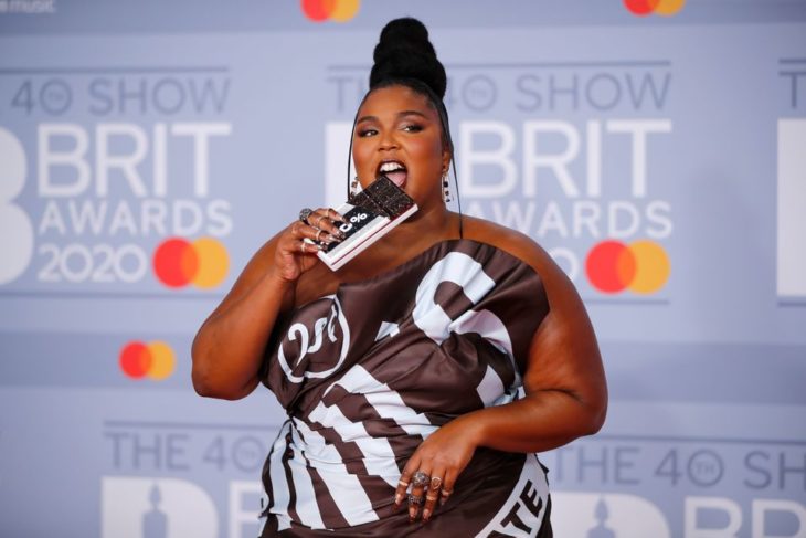 Lizzo usando un vestido con estampado de chocolate y simulando comer su bolso de chocolate