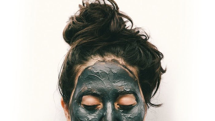Chica mostrando su frente con mascarilla de carbón activado