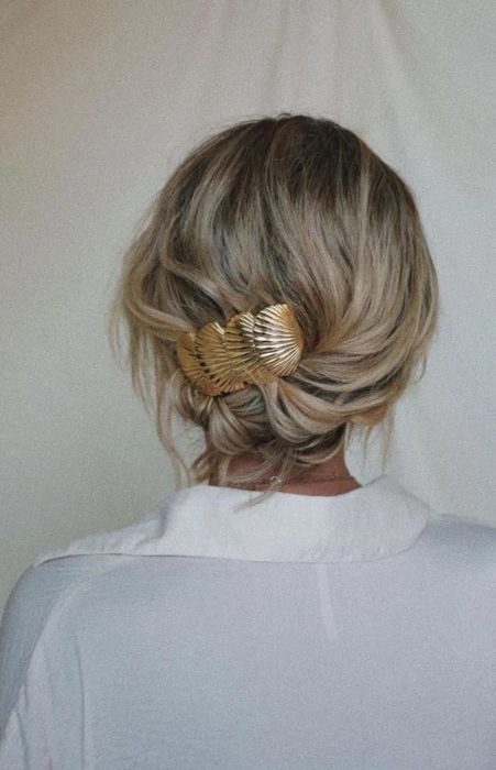 Chica rubia con recogido despeinado y broche dorado