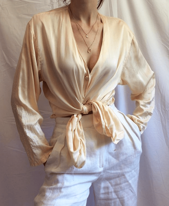 Chica con blusa de satén beige y pantalón blanco