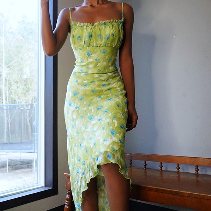 mujer morena usando un vestido verde con tirantes, escote recto y un estampado de flores blancas