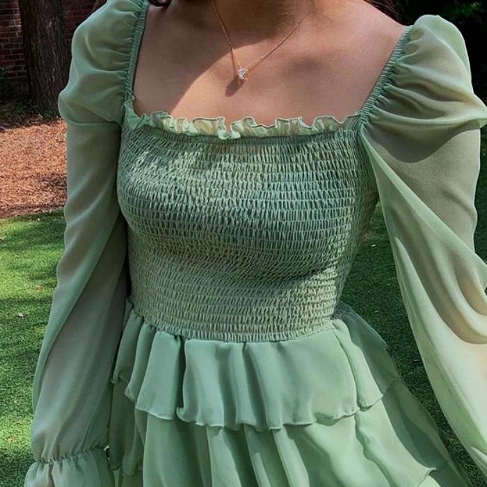 mujer usando un vestido verde con volantes y gaza, escote cuadrado y ajustado al cuerpo