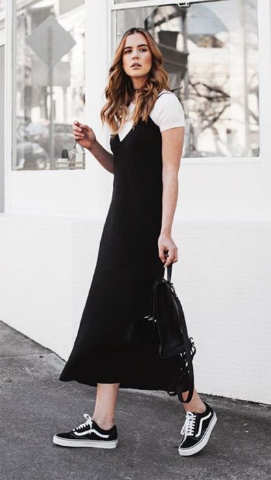 Chica rubia delgada con cabello suelto en vestido largo y negro con blusa blanca debajo