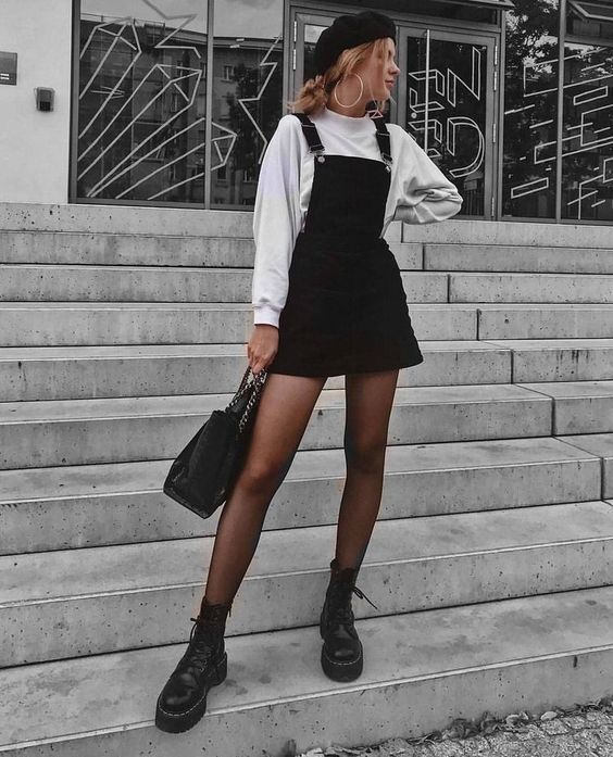 Chica rubia delgada posando con vestido negro de pana y sudadera blanca
