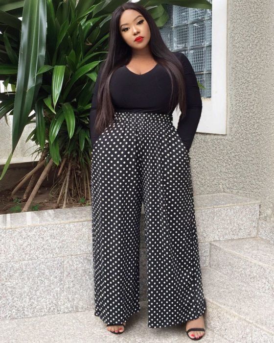 Chica curvy usando blusa negra ajustada y palazzo negro con lunares blancos