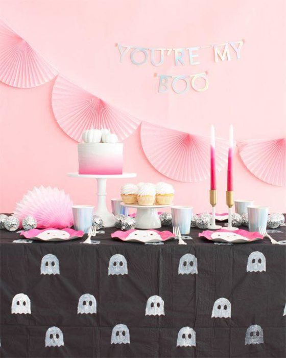 Mesa de dulces para Halloween con mantel negro con fantasmas y pared rosa pastel