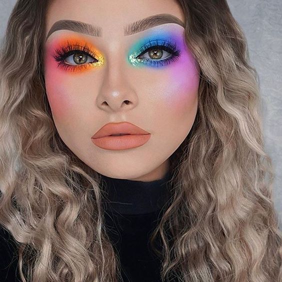 Chica rubia de cabello rizado con maquillaje de ojos coloridos y labio nude