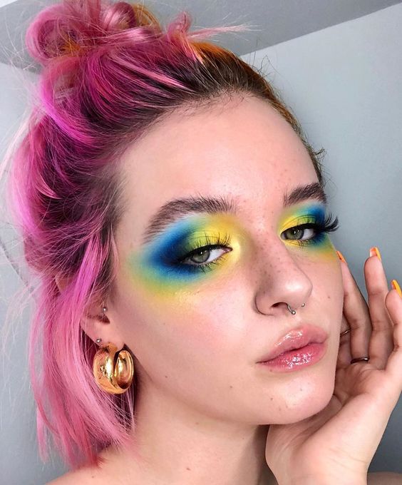 Chica blanca de cabello rosa corto con maquillaje amarillo y azul