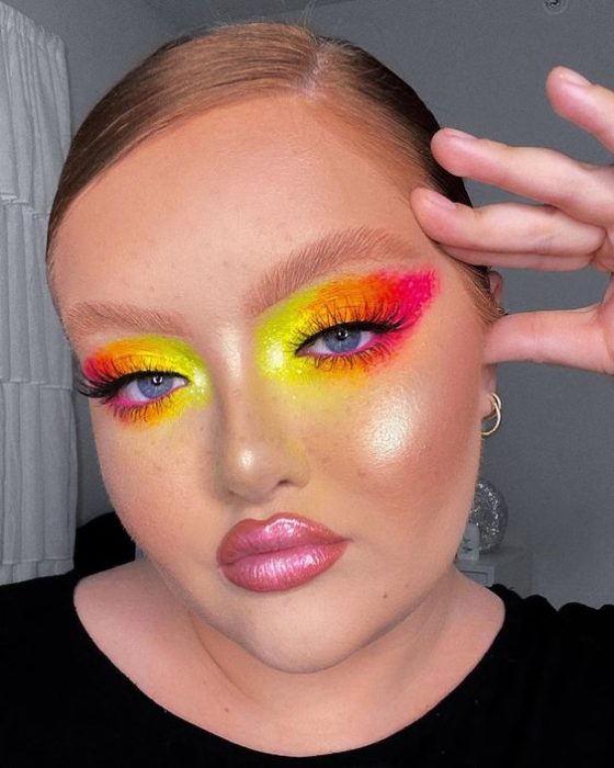 Chica rubia con coleta y maquillaje vibrante en rosa, naranja y amarillo