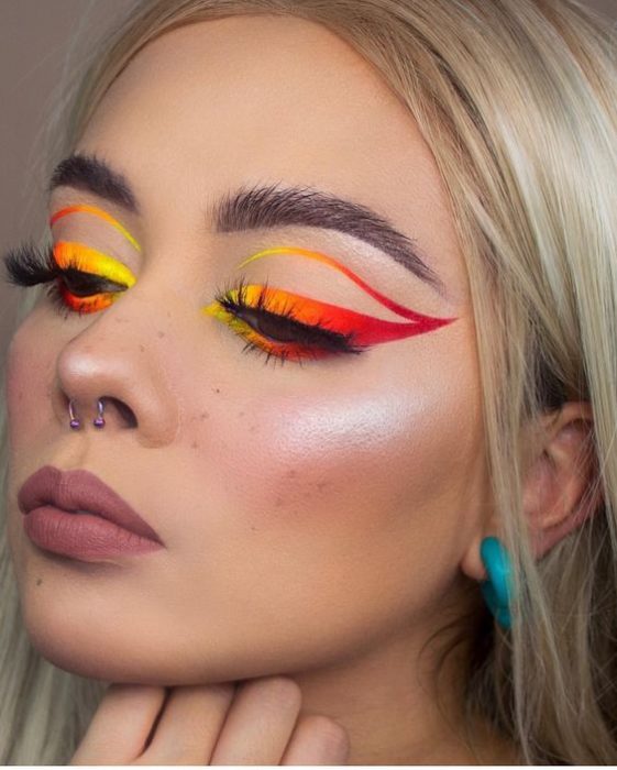 Chica rubia de cabello lacio con delineado gráfico en rojo y amarillo