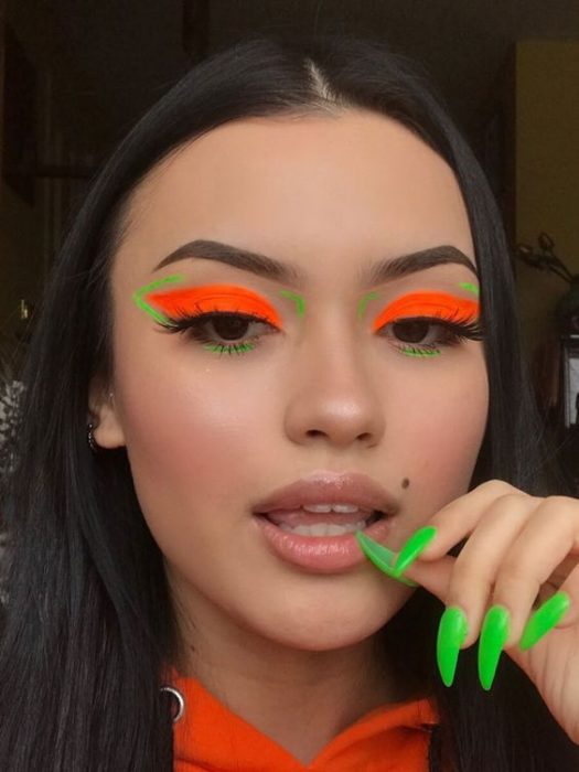 Chica morena clara con maquillaje de ojos en naranja y verde neón