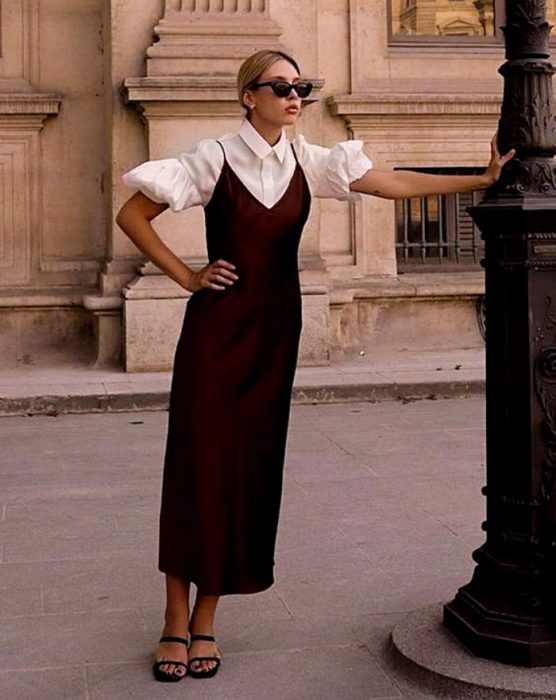chica rubia con lentes de sol, usando una blusa blanca de mangas de globo con vestido de satén guinda y sandalias de tacón