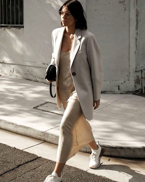 chica de cabello castaño largo usando un vestido beige claro de satén slip dress con tenis deportivos blancos, blazer oversized