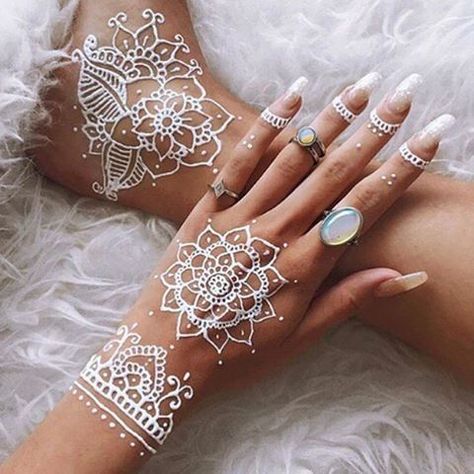 Tatuaje de henna blanca en la mano derecha con uñas largas transparentes