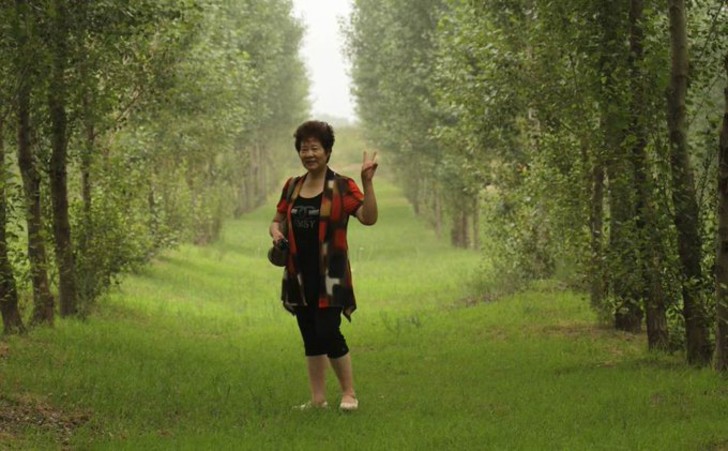Yi posando entre los árboles adultos, después de 12 años de haberlos plantado