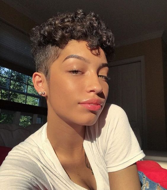 Chica morena con cabello rizado corto estilo pixie