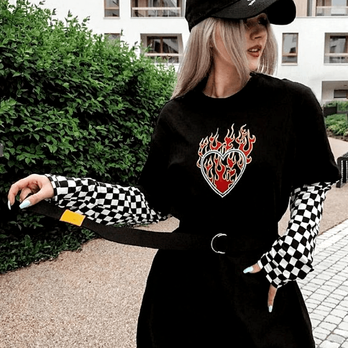 chica usando gorra negra, camiseta negra y mangas de cuadros blancas y negras con pantalón a la cintura y cinturón negro