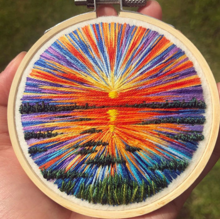 Bordado en aro hecho a mano de el reflejo de un atardecer en el agua
