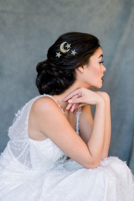 Mujer con cabello recogido suelto y broches dorados en forma de estrellas y luna