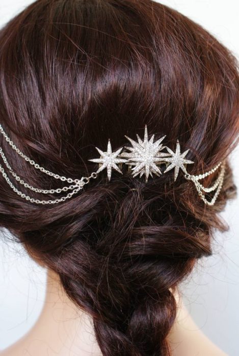 Chica de cabello oscuro con un chongo y broches de estrella y cadenas plateadas