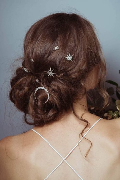 Chica de cabello castaño claro con chongo desenfadado y broches de estrellas