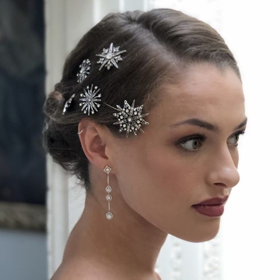 Novia de cabello recogido en un chongo bajo con broches en forma de estrellas