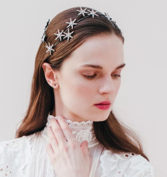 Chica blanca con vestido de novia y cabello suelto usando un tocado de estrellas 