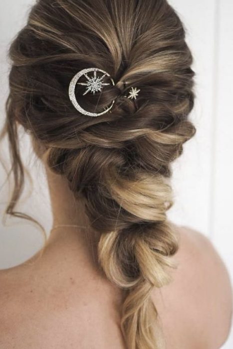 Novia de cabello rubio con recogido deshecho y broche de luna y estrella