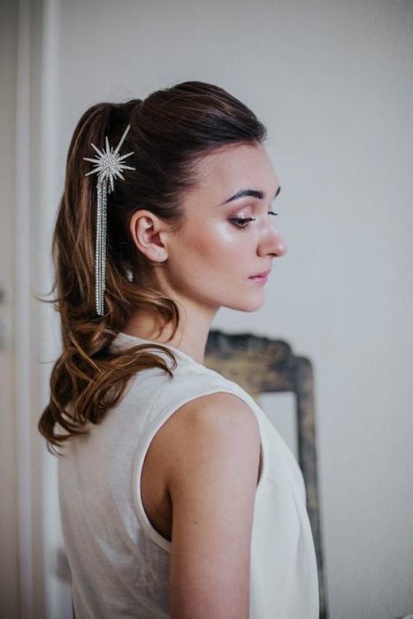 Chica de cabello recogido en una coleta alta con un accesorio de estrella y una cadena colgando