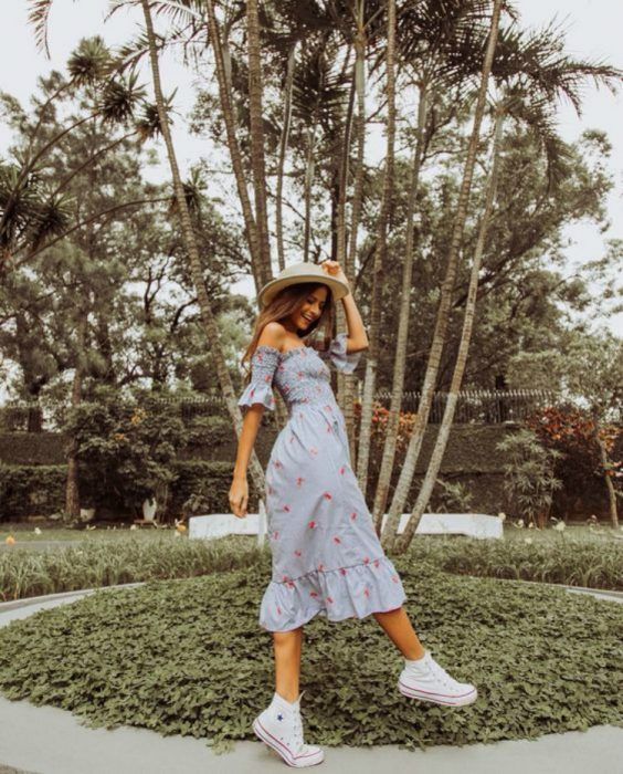 Chica usando outfit veraniego de vestido midi, off the shoulder, tenis blancos, y sombrero de paja