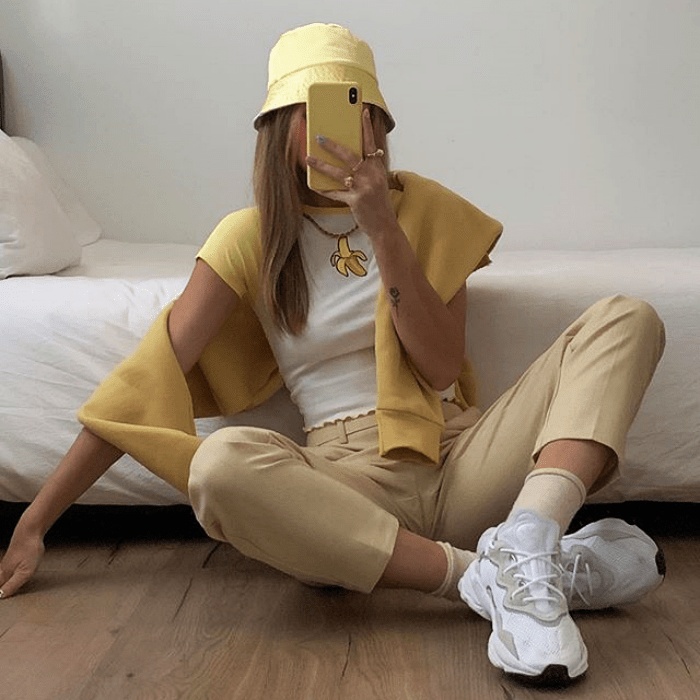 chica usando conjunto de color amarillo, bucket hat, playera blanca, pantalones cortos amarillos, tenis blancos y suéter amarillo