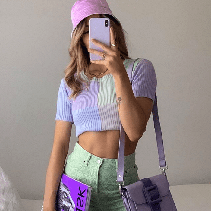chica usando bucket hat morado, top lila, pantalones color pistache y bolso morado
