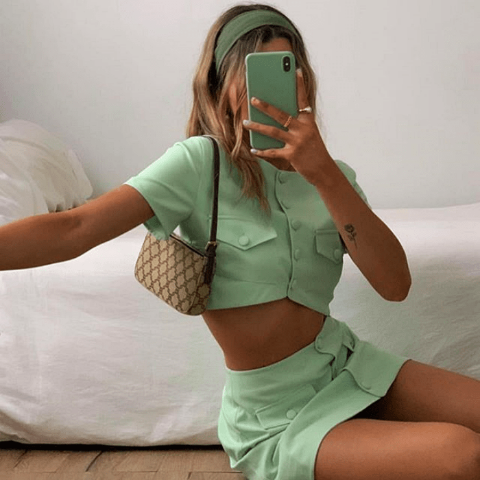 chica usando conjunto color menta, con camisa crop top, minifalda y bolso de mano café y beige