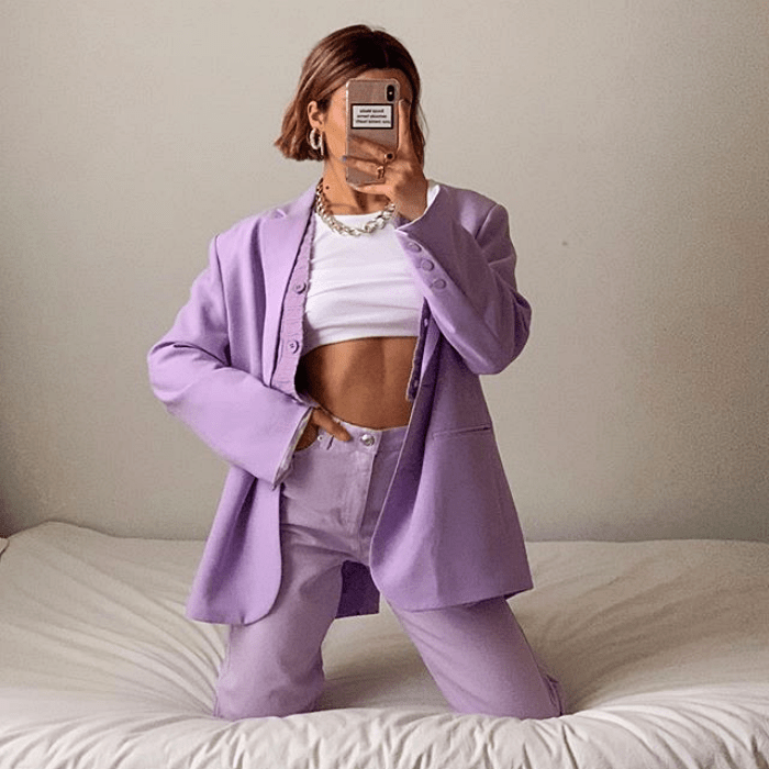 chica usando top blanco crop-top, saco lila y pantalones de vestir lila