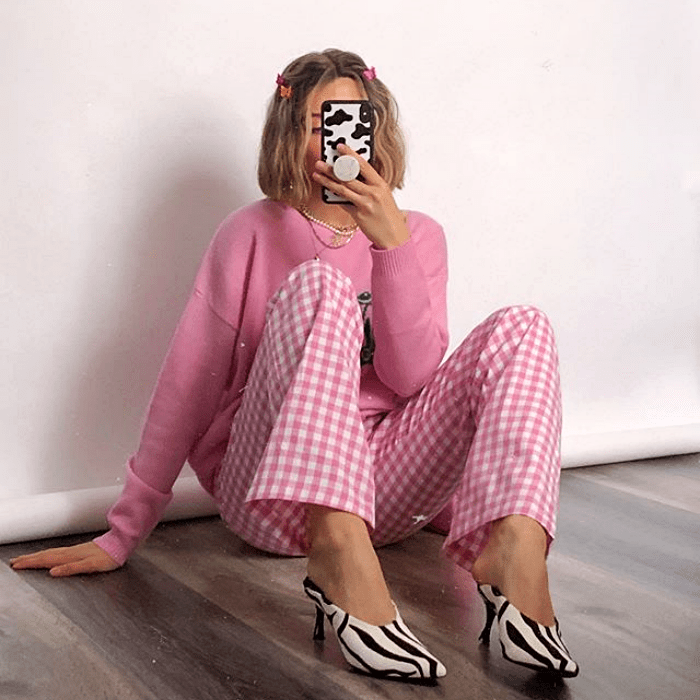 chica rubia usando suéter rosa, pantalones rosas con cuadros blancos y zapatos de tacón con estampado de cebra