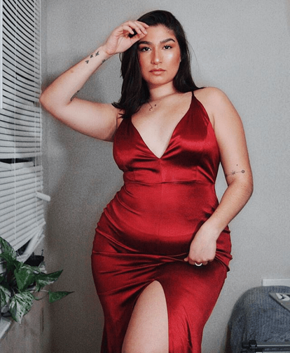 Chica de cabello castaño largo en un vestido ceñido curvo rojo con escote en V y abertura en la pierna