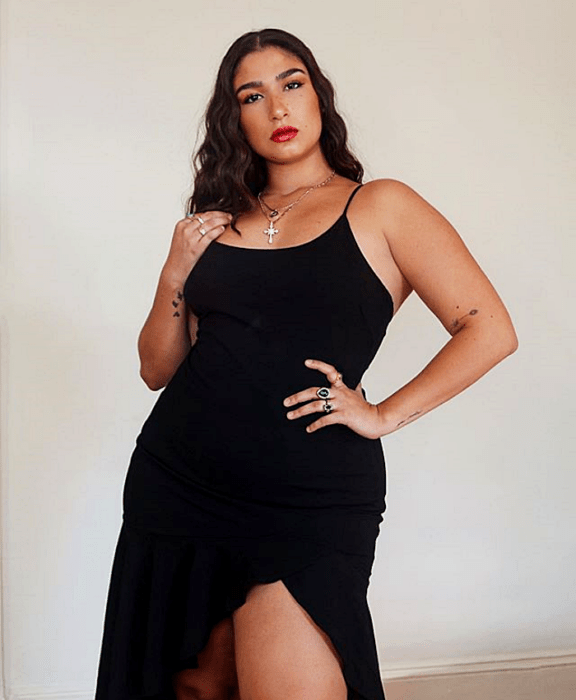 Chica de cabello castaño largo en un vestido ceñido negro de tirantes