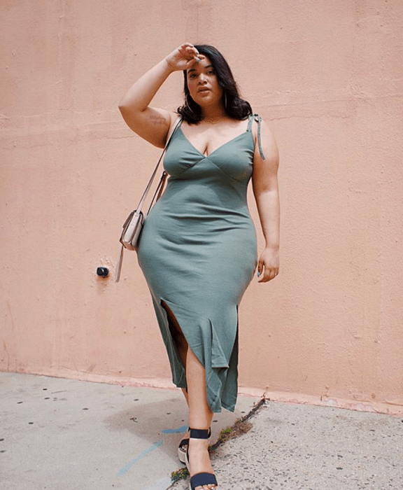 Chica curvy en un vestido color verde opaco con escote en V y tirantes