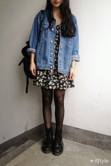 Chica morena de cabello largo y oscuro con vestido corto floreado y chaqueta de mezclilla usando botas dr. martens