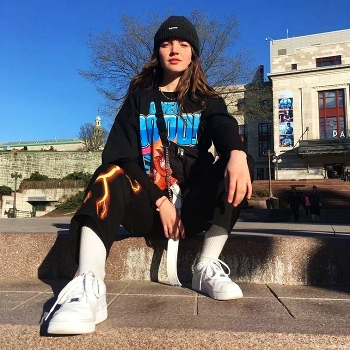 Chica con camiseta oversized negra con letras azules y pantalones negros con llamas