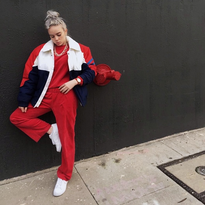 Billie Eilish con una chamarra bomber y pantalones rojos