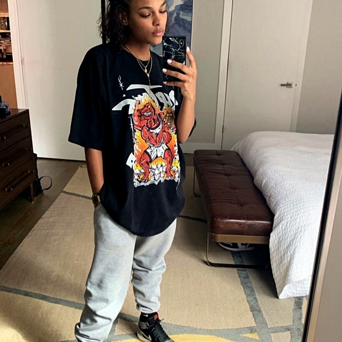 Chica con camiseta oversized negra y pantalones grises deportivos
