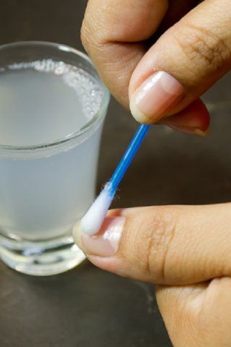 Chica aplicando mezcla de vinagre de manzana en sus uñas