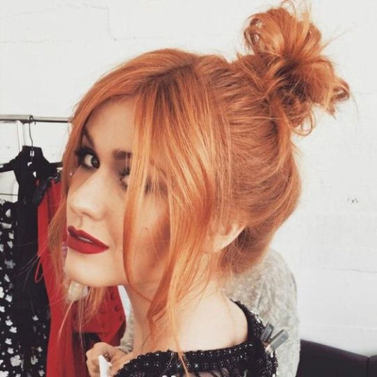Chica con cabello peinado en bun y teñido en efecto peachy copper